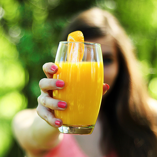 woman holding orange juice glass