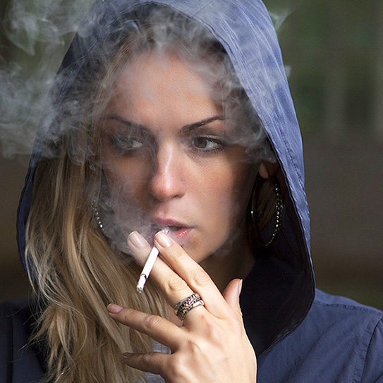 woman wearing hood and smoking cigarette