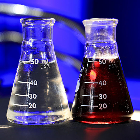 Two lab flasks filled with white and red liquids