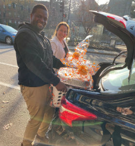 A man and a woman loading packages into the trunk of a car