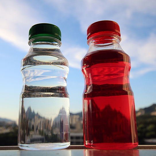 bottle of red juice next to a bottle of water