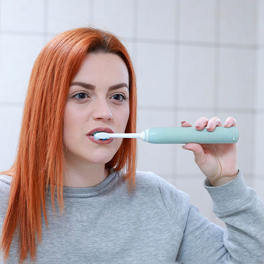 young woman using electric toothbrush