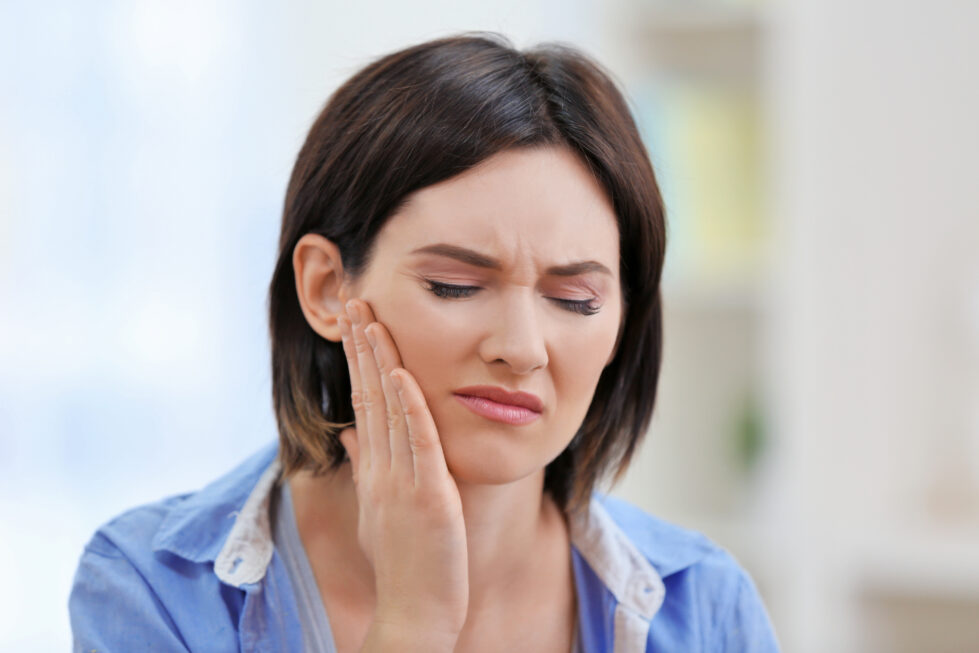 Beautiful young woman suffering from toothache at home
