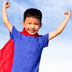 boy with superhero cape and arms up