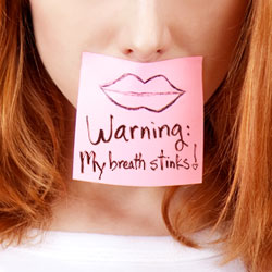 woman with a sign that reads warning my breath stinks